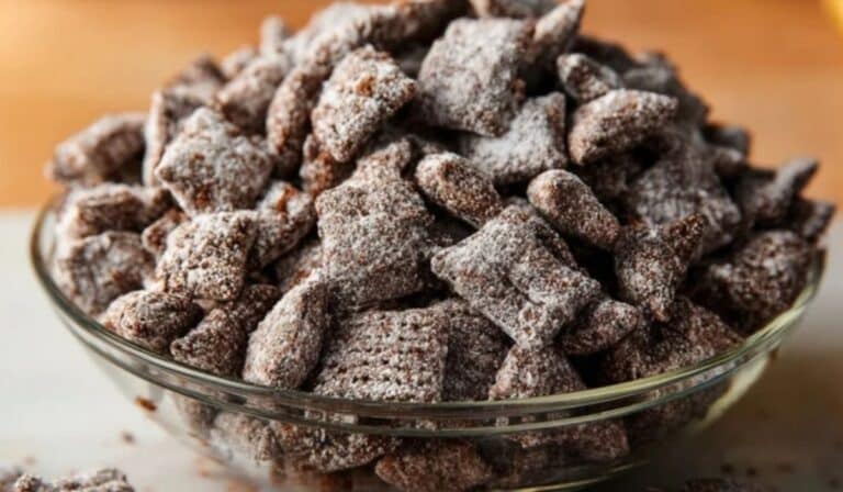 Brownie Batter Puppy Chow in bowl dusted with powdered sugar