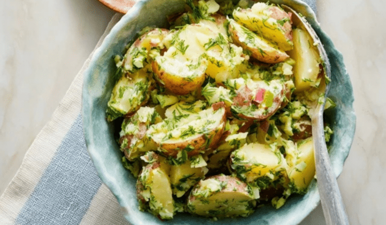 Herbed potato salad with lemon Dijon dressing and fresh herbs in a serving bowl